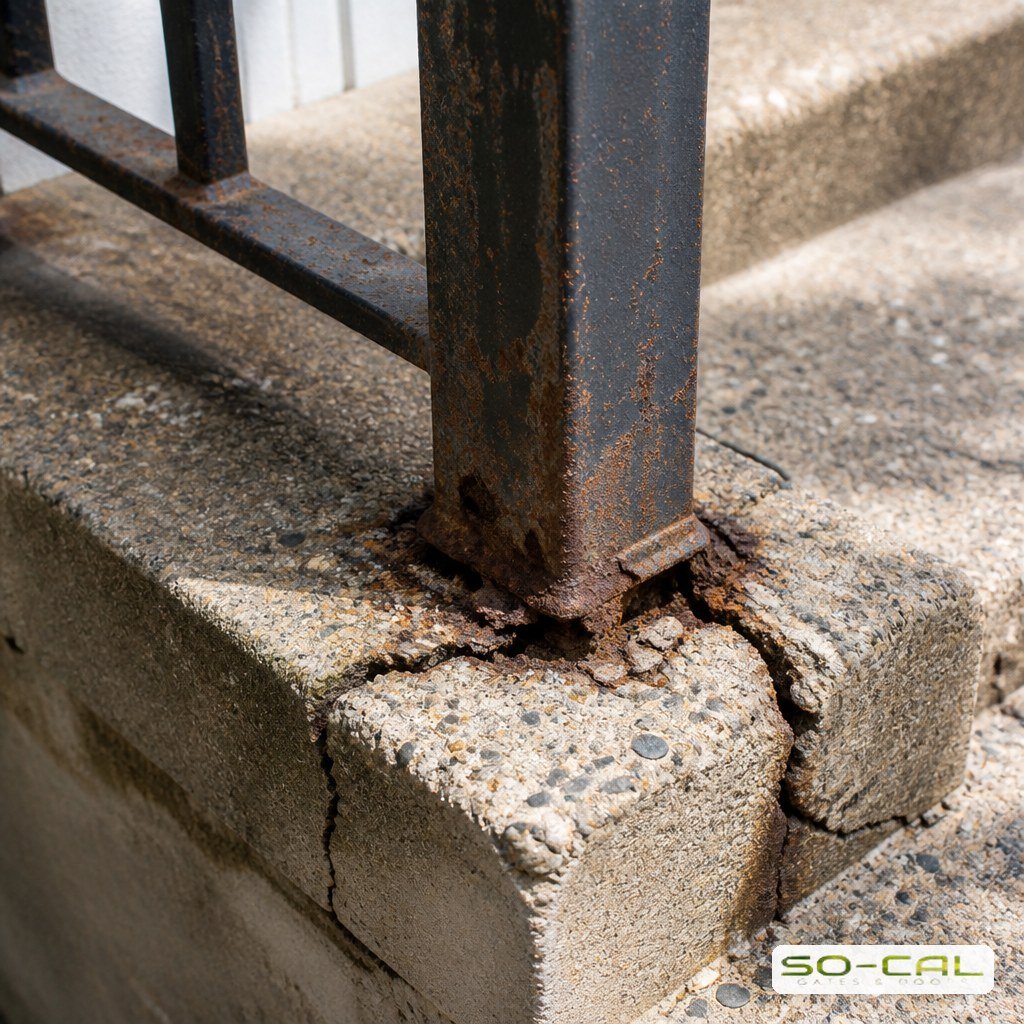 Rusted iron railing post corroding where it meets concrete